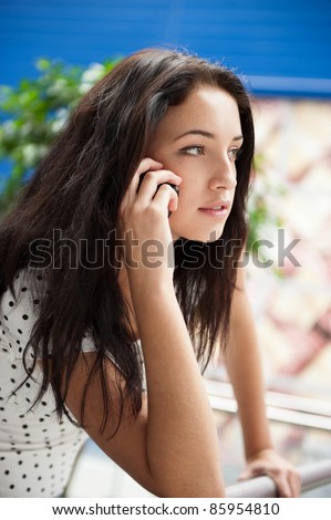 Portrait of young pretty woman talking with someone using cell phone. Indoors