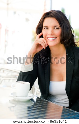 Closeup portrait of cute young business woman smiling while drinking her coffee at outdoor cafe