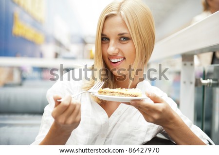 Portrait of young pretty smiling woman eating cake at shopping mall cafe