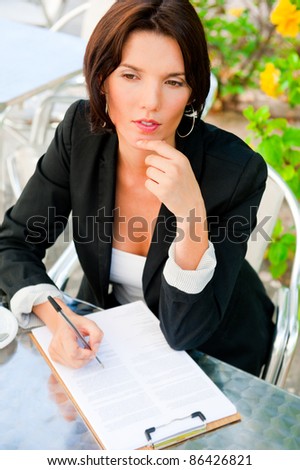 Business woman working with documents while having lunch or breakfast coffee at outdoor cafe near her office