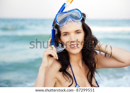 Young hispanic woman with wet skin and with a snorkel standing on beach after going to swim in clear mediterranean sea