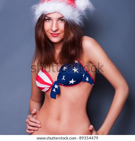 20-25 years old beautiful woman in Christmas hat and swimsuit with American flag