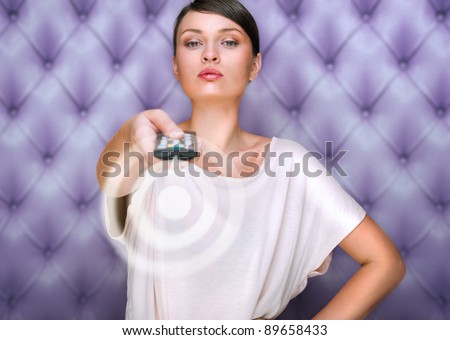 Portrait of a beautiful fashionable elegant woman with remote control choosing channels. Vintage luxury background