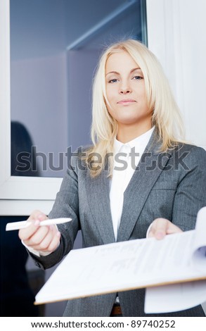 Portrait of young business woman wearing formal clothes giving contract to sign at her office