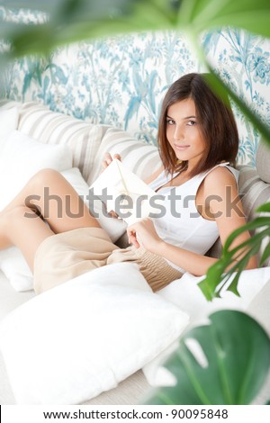 Delighted woman reading a greeting card sitting on the sofa at home