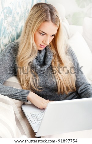 Woman on sofa in living room looking at her laptop while chatting