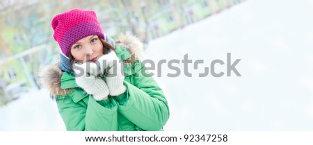 Winter woman in snow looking at camera outside on snowing cold winter day. Portrait Caucasian female model outside in first snow