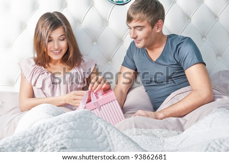 Young happy couple presenting gift in bed