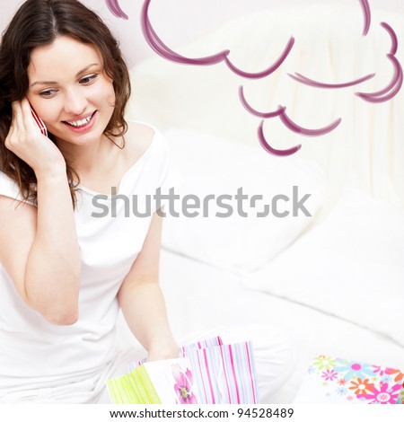 Portrait of young beautiful awake woman with gifts on bed at bedroom. Talking with her boyfriend by mobile phone. Cloud balloon overhead