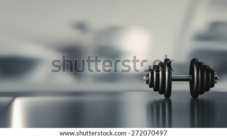 Dumbbell on a reflective floor with space for text.