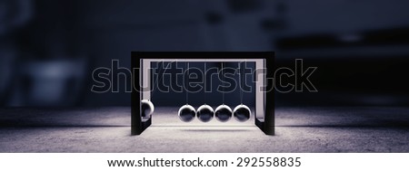 Newton cradle with stylish artistic backlight in dark scene. Image easy to crop to achieve space for text on right or left side.