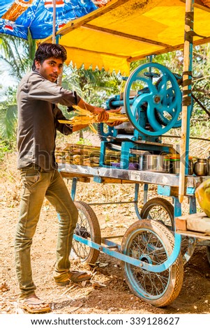 GOA, INDIA - FEBRUARY 2015: Man making a fresh cane juice on a country road in Goa, India. Sweet cane juice produced for clients.