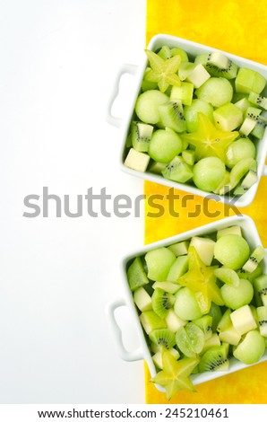 fresh healthy fruit salad and ingredients on yellow background with free space
