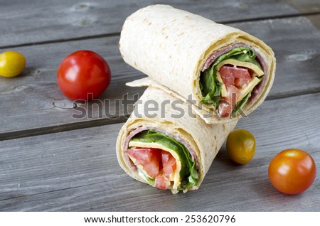 wrap sandwich with salami, lettuce, tomatoes and cheeses