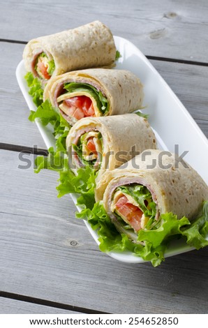 wrap sandwich with salami, lettuce, tomatoes and cheeses