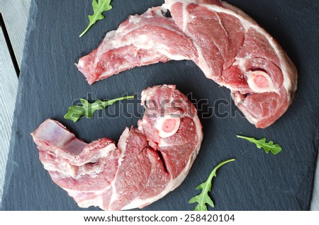 A lamb shoulder chops. Raw meat on black stone.