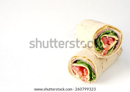 wrap sandwich with salami, lettuce, tomatoes and cheeses on white background with copy space.