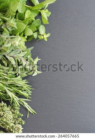 Fresh Kitchen Herbs for lamb oregano, mint, rosemary, lemon thyme on black stone as texture or background