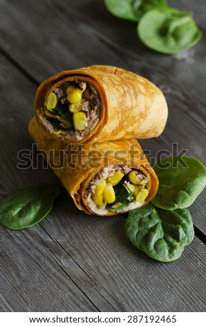wrap sandwich with pink salmon, conr, and spinach in tomato wrap