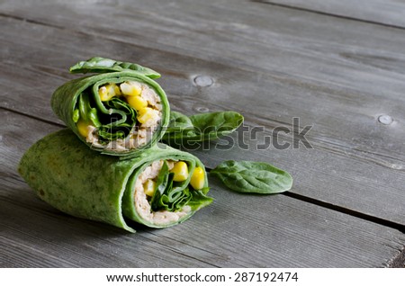 wrap sandwich with pink salmon, conr, and spinach in spinach wrap