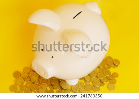 Piggy bank with coins on yellow background