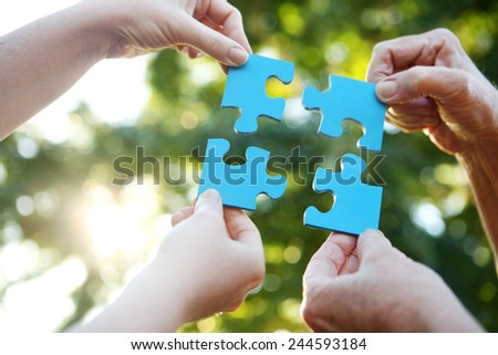 Four hands holding up a jigsaw puzzle