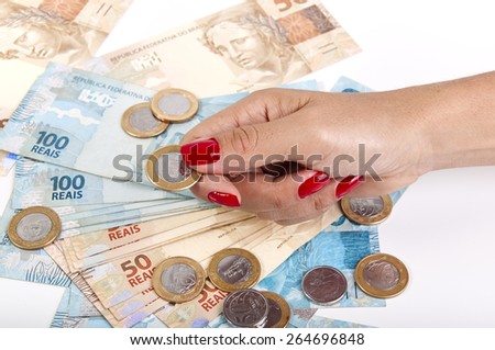 Woman\'s hand holding a Brazilian coin and mirrored money on white background