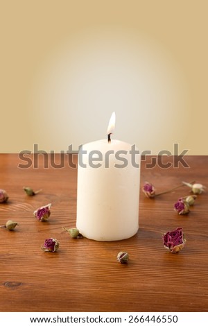 burning candle on a table scattered with flowers