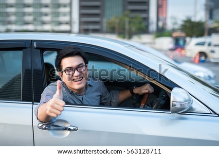 Young man doing thumps-up in car he so happy