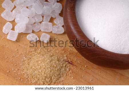 White sugar, crystal sugar and cane sugar on a wooden background