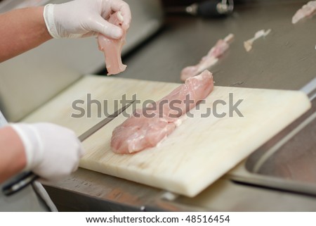 Cutting chicken fillets in a restaurant kitchen