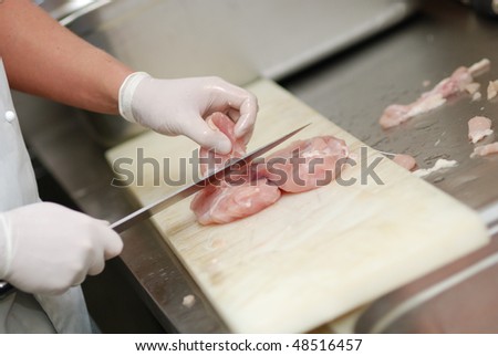 Cutting chicken fillets in a restaurant kitchen