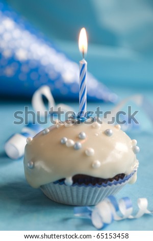 Birthday muffin with blue candle on blue background