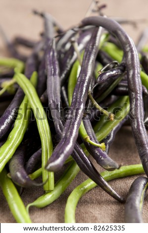 Fresh raw violet runner beans on wooden background