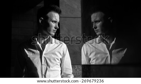 handsome young man and his reflection in the mirrored wall