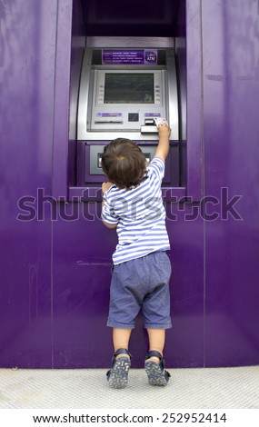 CHIANG MAI, THAILAND, FEBRUARY 10, 2015: A Little Boy Trying to Get Money at an SCB Bank ATM Machine. Siam Commercial Bank is the first bank of Thailand, informally established in 1904 as Book Club.