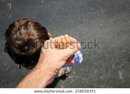 Little Child Holding His Fathers Hand Tightly On The Side Of The Road. Dads Perspective.