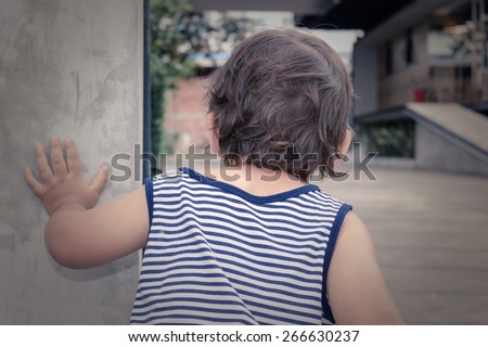 Little Boy Looking Around The Corner of a Little Concrete Wall