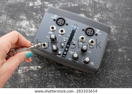 Audio interface for recording or mixing - sound/audio card - woman's hand holding audio plug -  grunge background