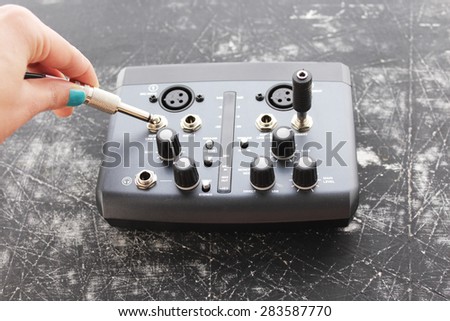 Audio interface for recording or mixing - sound/audio card - woman's hand holding audio plug -  grunge background