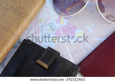 Preparation for travel - sunglasses, passport, wallet and notebook - on world map with place for text in the middle - vintage style