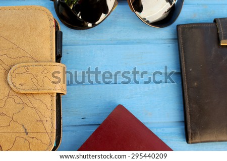 Preparation for travel - sunglasses, passport, wallet and notebook - on blue wooden table with place for text in the middle - vintage style