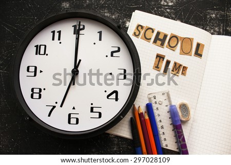 It is time for school concept - school equipment on notebook - on blackboard background