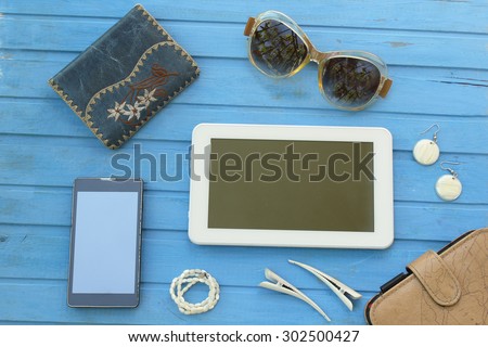 Woman\'s things for traveling - wallet, sunglasses, earrings, necklace, notebook, hair clips, tablet computer and smart phone