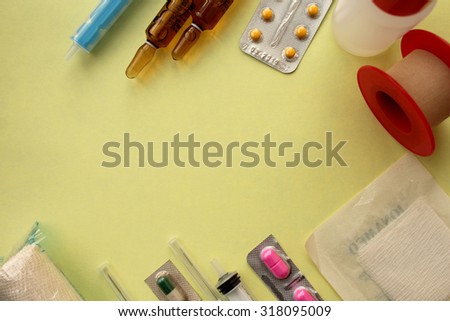 Medicine concept for first help -pill, bottle, tablet, syringe, needle, ampules, bandage and plaster  - copy space on soft yellow background