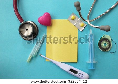 Medical theme -pill, syringe, needle, medical thermometer, surgical thread, stethoscope and sticky note - copy space on pink background