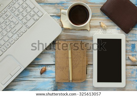 Top view of office table top with laptop computer, coffee cup, notebook planner, pen, tablet computer, wallet and decoration