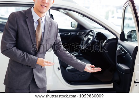 Young chauffeur in business suit welcoming rich and wealthy client on board - rich lifestyle taxi car transportation concept