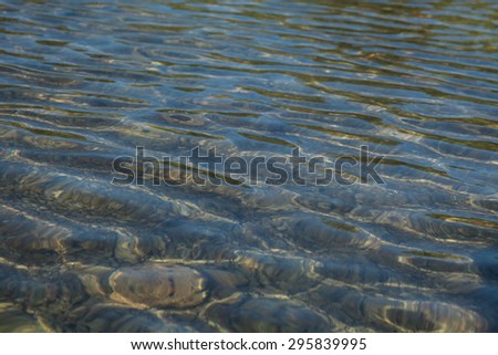 Abstract background of ripples on water surface on sea shore. Beautiful natural abstract background. It\'s crystal clear see through.