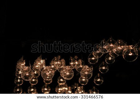 Abstract background of many hanging light bulbs in the dark room. (Selective focus, blur out the some light bulbs for aesthetic quality)